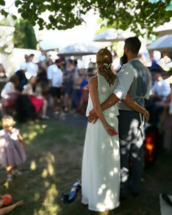 Brautpaar umarmt sich im Schatten auf einer Hochzeitsfeier im Freien