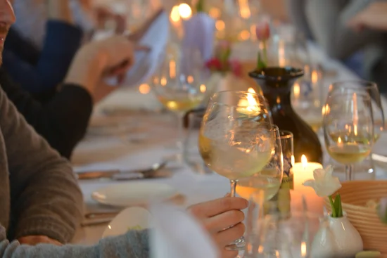 Menschen sitzen an einem langen Tisch mit wein und Kerzenlicht