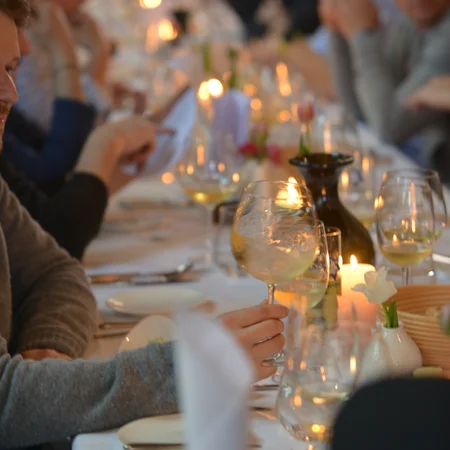 Menschen sitzen an einem langen Tisch mit wein und Kerzenlicht