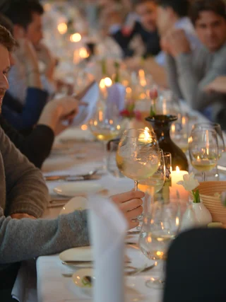 Menschen sitzen an einem langen Tisch mit wein und Kerzenlicht