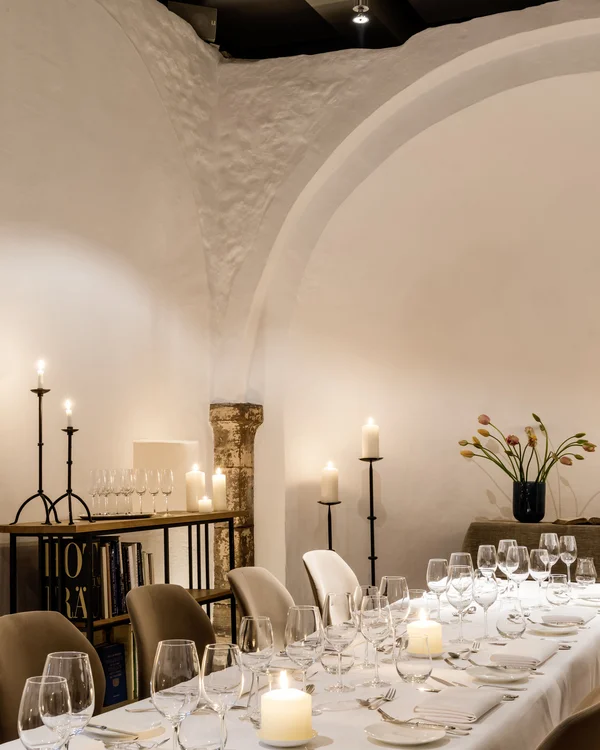 Eleganter gedeckter Esstisch mit Kerzen und Weingläsern in einem Raum mit Bogenwänden