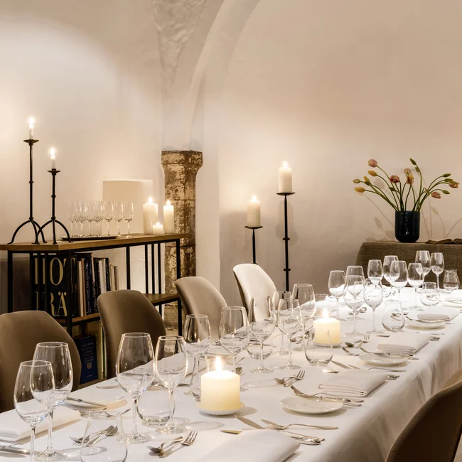 Eleganter gedeckter Esstisch mit Kerzen und Weingläsern in einem Raum mit Bogenwänden