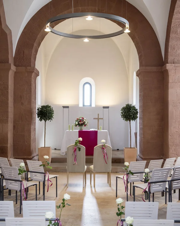 Innenansicht einer Kirche mit dekorierten Stühlen und Altar für Hochzeit