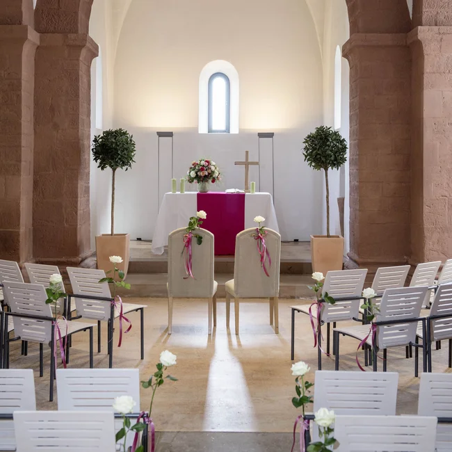 Innenansicht einer Kirche mit dekorierten Stühlen und Altar für Hochzeit