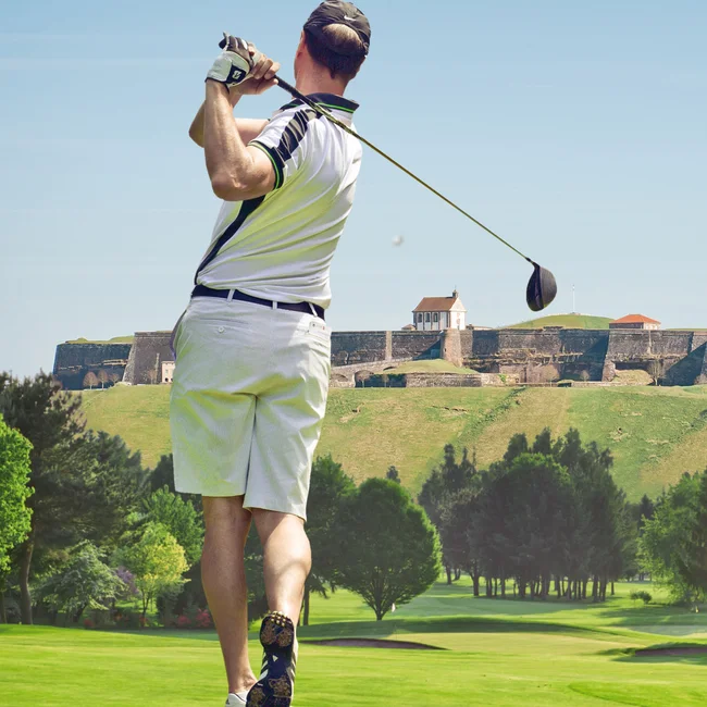 Mann spielt Golf auf grünem Golfplatz mit historischer Burg im Hintergrund