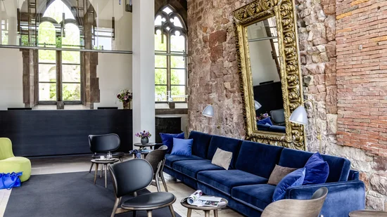 Moderner Wartebereich mit blauer Couch, Stühlen und großer verzierten Spiegelwand