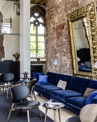 Moderner Wartebereich mit blauer Couch, Stühlen und großer verzierten Spiegelwand