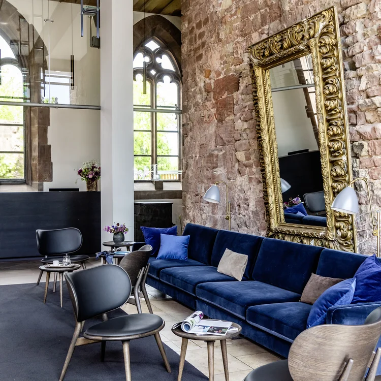 Moderner Wartebereich mit blauer Couch, Stühlen und großer verzierten Spiegelwand