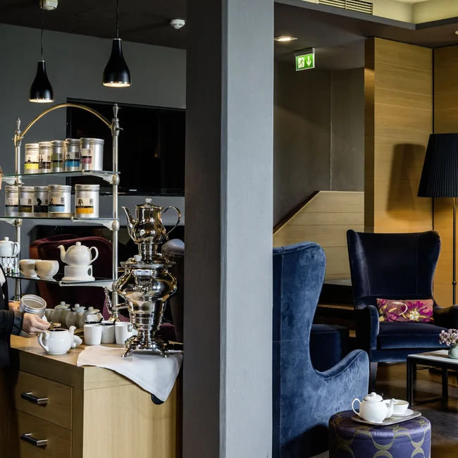 Frau bereitet Tee an einem modernen Tee- und Kaffeebuffet in einer Lounge zu