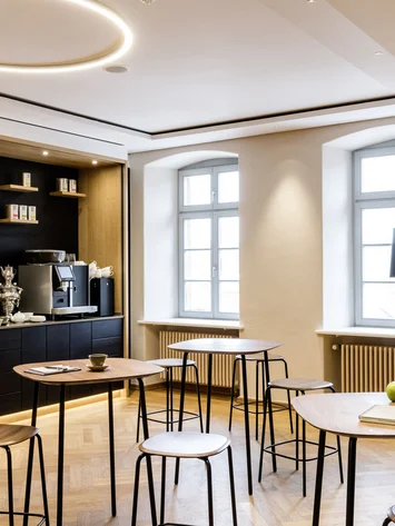 Modern eingerichteter Aufenthaltsraum mit Stehtischen, Kaffeemaschine und Dekoration