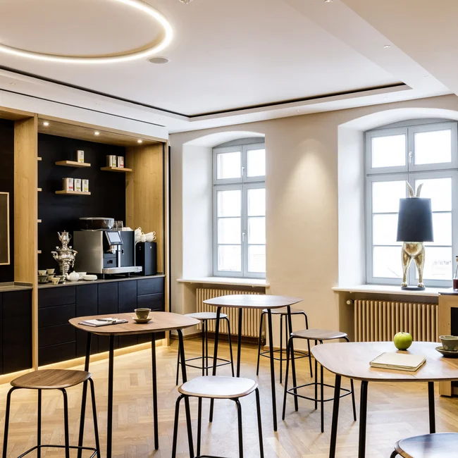 Modern eingerichteter Aufenthaltsraum mit Stehtischen, Kaffeemaschine und Dekoration