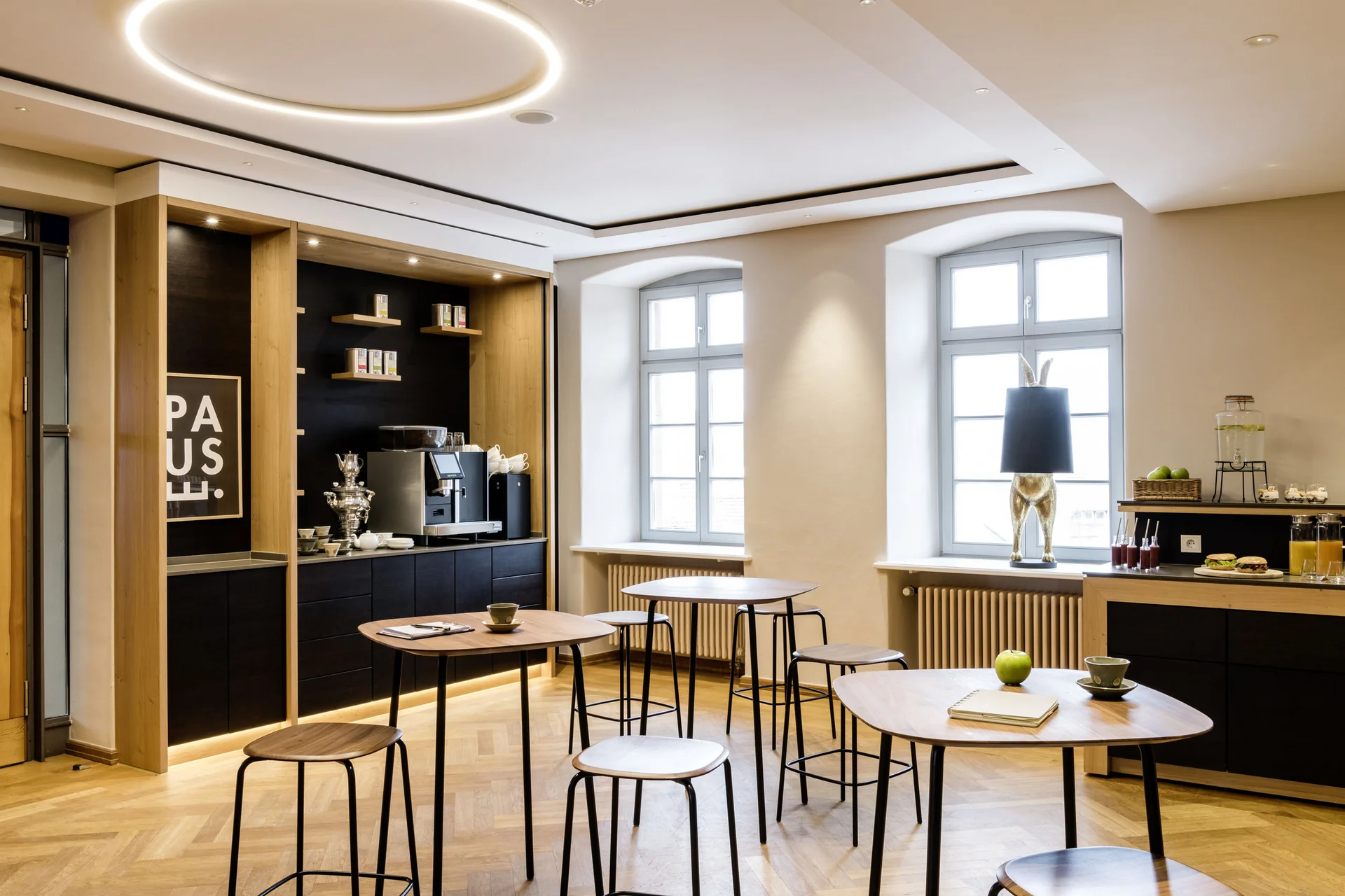 Modern eingerichteter Aufenthaltsraum mit Stehtischen, Kaffeemaschine und Dekoration