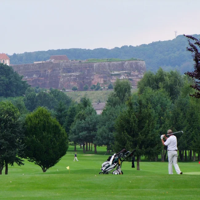 Golfer auf einem Golfplatz mit Bäumen und einer Burg im Hintergrund