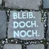 Pflastersteine mit dem weißen Schriftzug BLEIB. DOCH. NOCH.