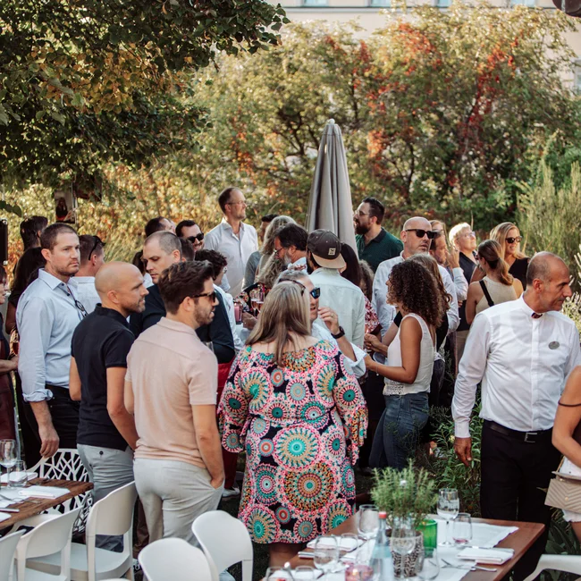 Menschen versammeln sich bei einem Outdoor-Event im Garten mit gedeckten Tischen
