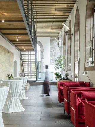 Moderne Lounge mit roten Sofas und Stehtischen in historischem Gebäude