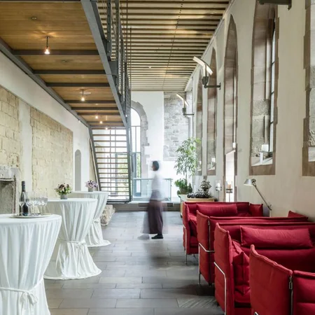 Moderne Lounge mit roten Sofas und Stehtischen in historischem Gebäude