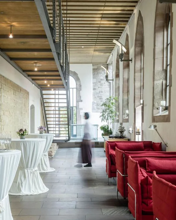 Moderne Lounge mit roten Sofas und Stehtischen in historischem Gebäude