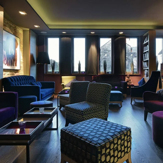 Gemütlicher Lounge-Bereich mit bunten Sesseln und Sofas vor großen Fenstern