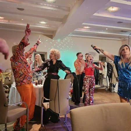 Menschen feiern und singen mit Mikrofon auf einer Party in bunten Outfits