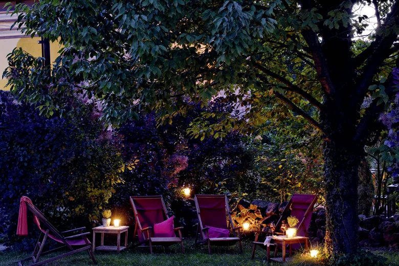 Abendliche Gartenbeleuchtung mit Stühlen und Kerzen unter einem Baum