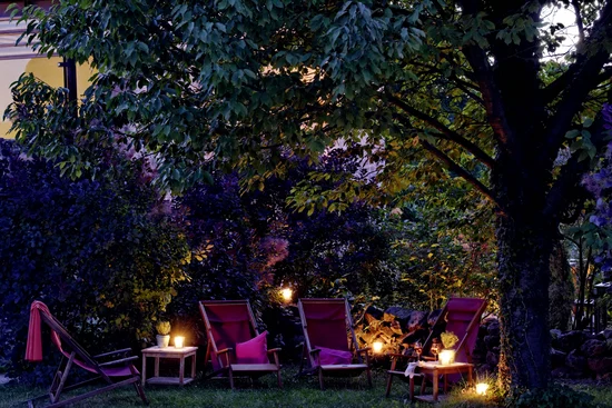 Abendliche Gartenbeleuchtung mit Stühlen und Kerzen unter einem Baum