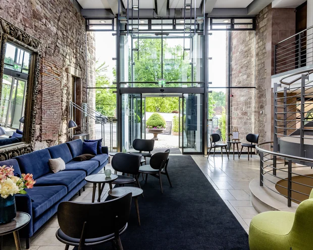 Moderner Wartebereich mit blauem Sofa, Stühlen und großer Glasfront mit Außensicht