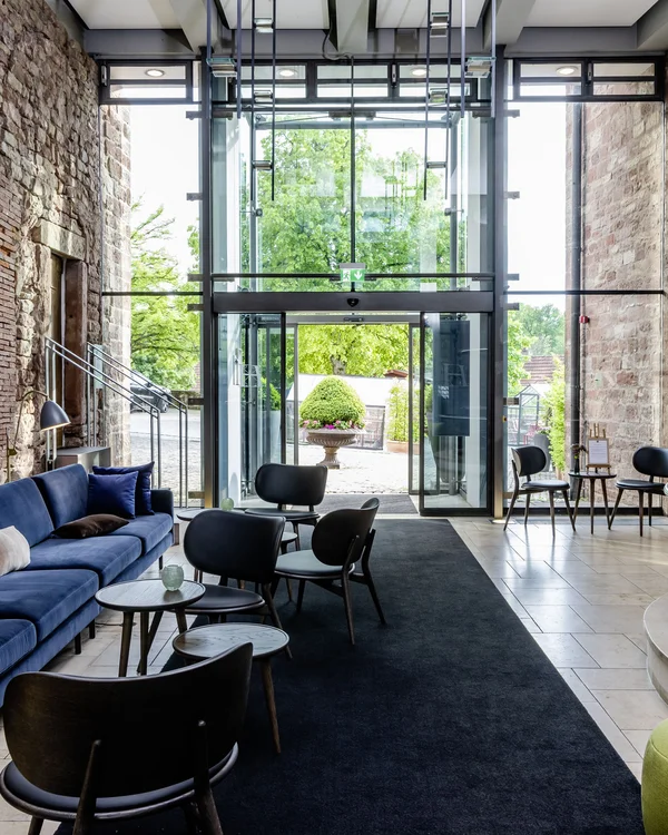 Moderner Wartebereich mit blauem Sofa, Stühlen und großer Glasfront mit Außensicht