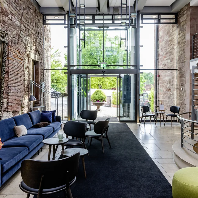 Moderner Wartebereich mit blauem Sofa, Stühlen und großer Glasfront mit Außensicht