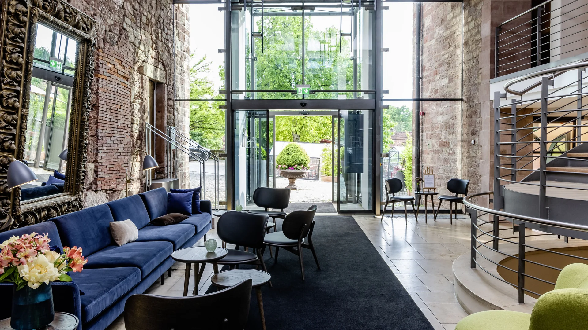 Moderner Wartebereich mit blauem Sofa, Stühlen und großer Glasfront mit Außensicht