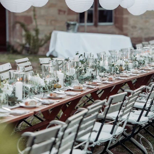 Lange Tischreihe mit Kerzen und Dekoration für festliches Outdoor-Essen