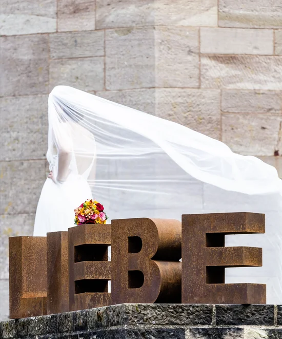 Braune Buchstaben leben mit Braut im weißen Kleid und Strauß im Hintergrund