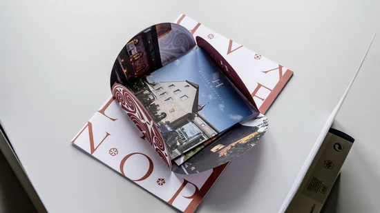 Aufgeschlagene Broschüre mit Bildern eines historischen Gebäudes und dekorativem Muster