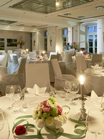Eleganter Bankettsaal mit festlich gedeckten Tischen und Blumenarrangements