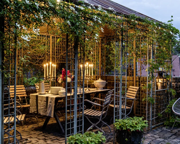 Abendessen im Gartenpavillon mit Kerzenlicht und blühenden Pflanzen