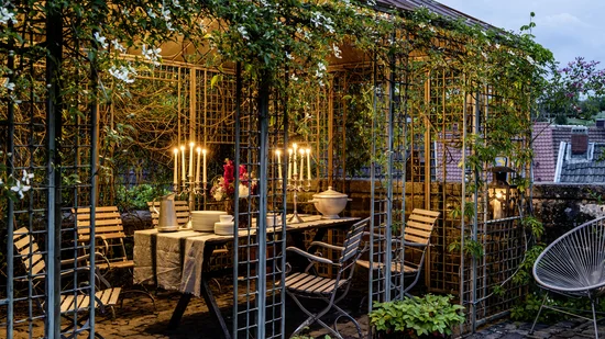 Abendessen im Gartenpavillon mit Kerzenlicht und blühenden Pflanzen