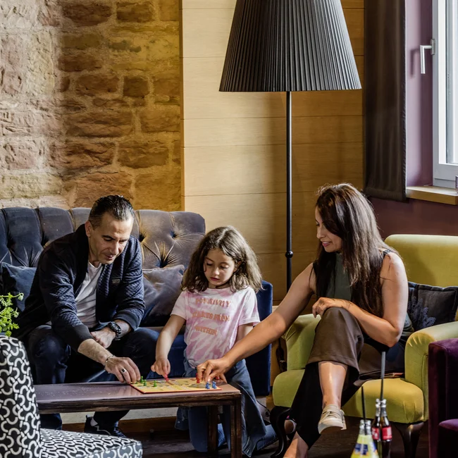 Familie spielt Brettspiel im Wohnzimmer mit Stehlampe und Sofa