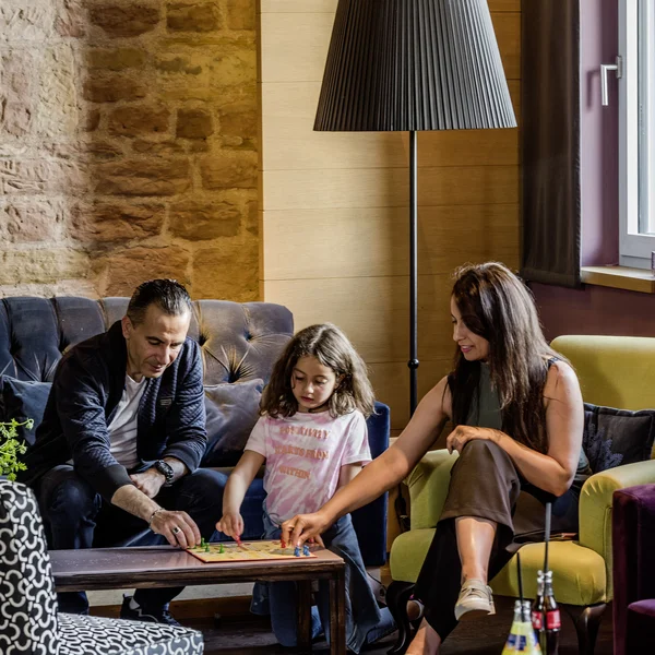 Familie spielt Brettspiel im Wohnzimmer mit Stehlampe und Sofa