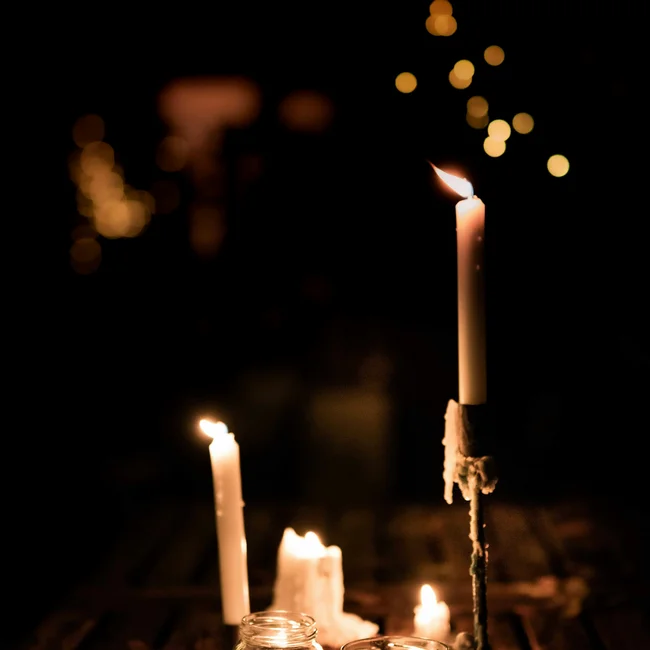 Brennende Kerzen auf Holztisch mit verschwommenen Lichtern im Hintergrund