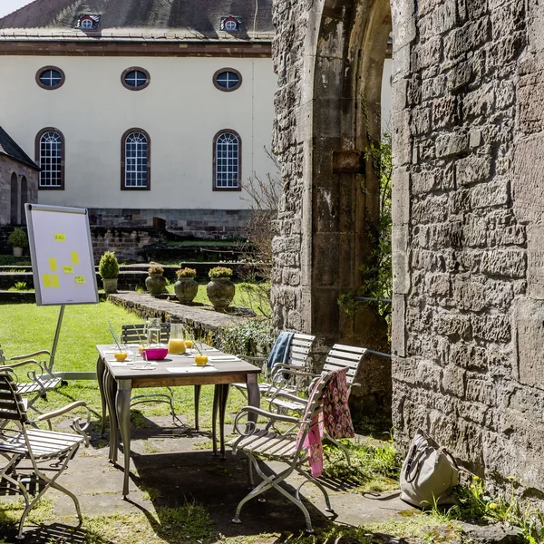 Outdoor-Meetingbereich mit Tisch, Stühlen und Flipchart in historischen Mauern