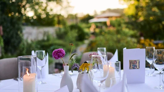 Eleganter gedeckter Außentisch mit Blumen, Kerzen und Gläsern im Garten