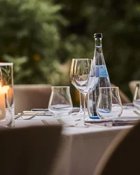 Eleganter gedeckter Tisch mit Kerzen und Wasserflaschen im Außenbereich