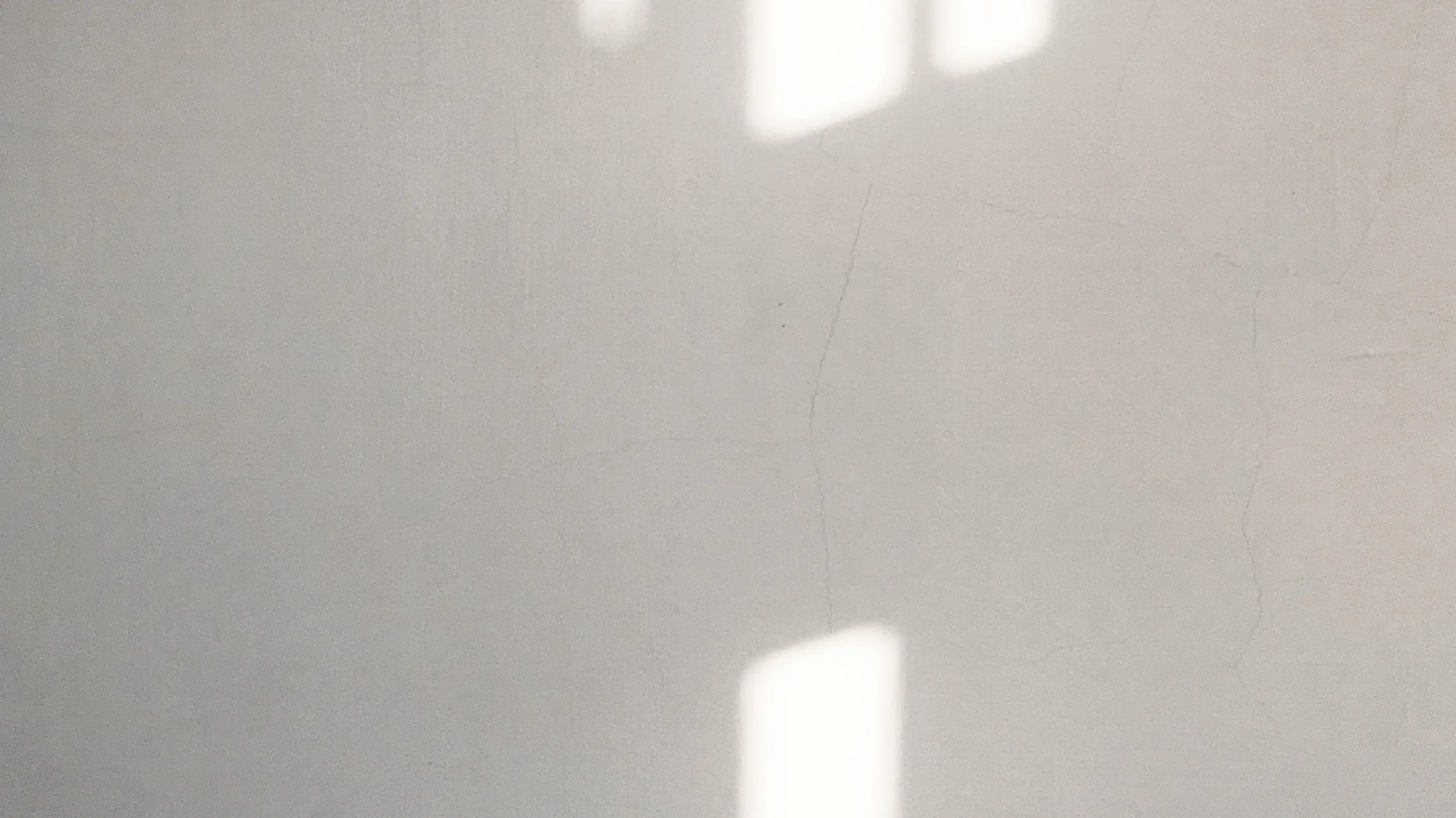 Sonnenlicht wirft rechteckige Schatten auf eine weiße Wand