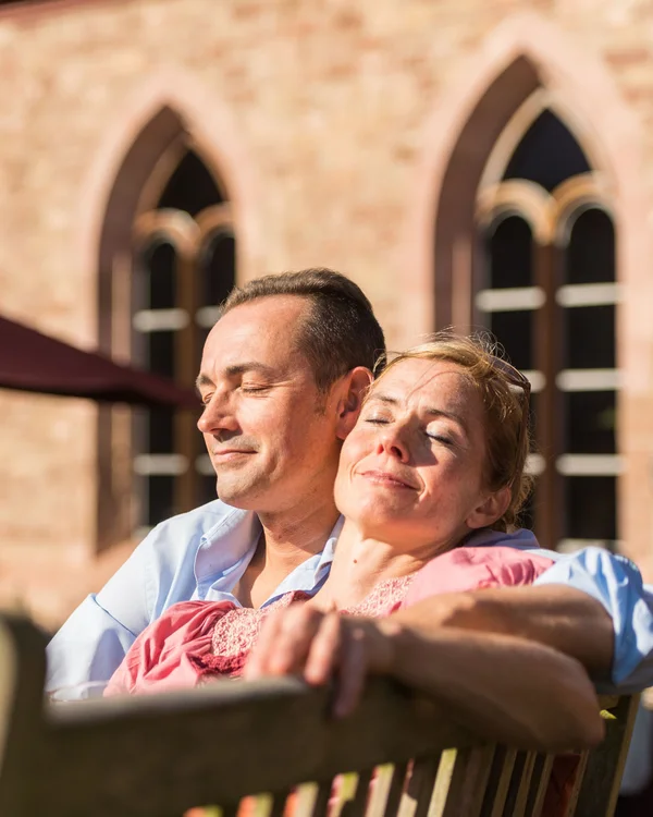 Kloster Hornbach FAQ Mann und Frau genießen entspannt die Sonne auf einer Bank vor einem Gebäude