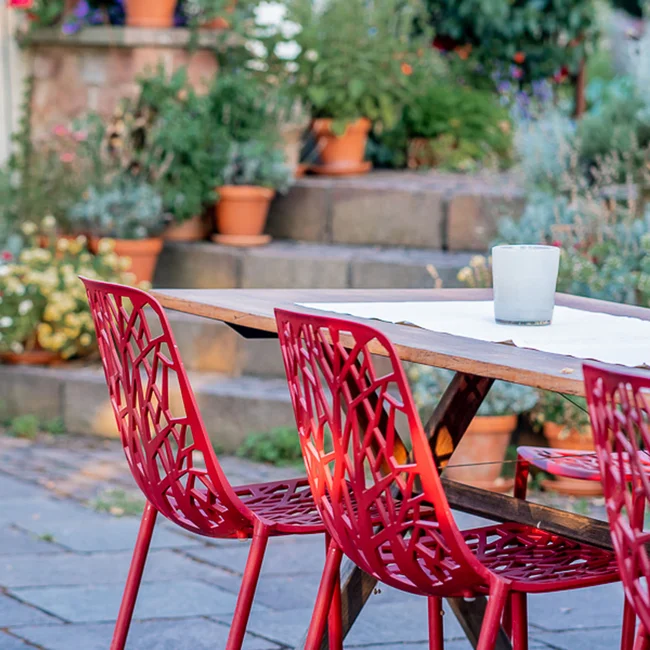 Roter Stuhl und Holztisch im Garten mit Topfpflanzen auf Treppen