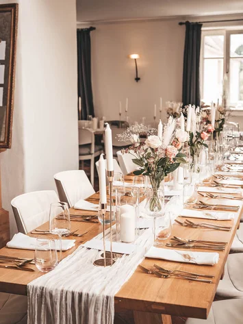 Eleganter, lang gedeckter Tisch mit Blumen und Kerzen in einem modernen Esszimmer