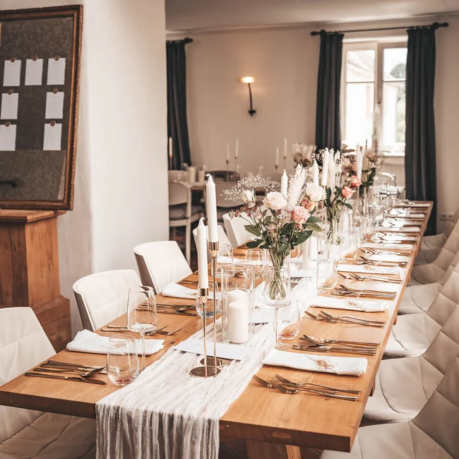 Eleganter, lang gedeckter Tisch mit Blumen und Kerzen in einem modernen Esszimmer