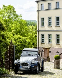 Klassisches Auto vor dem Hotel Kloster Hornbach umgeben von Bäumen