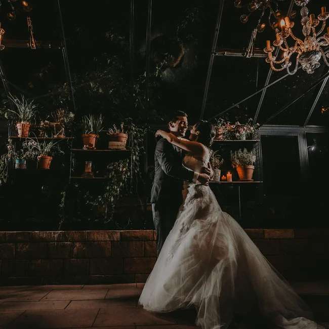 Brautpaar tanzt romantisch bei Nacht unter Kronleuchtern und Pflanzen
