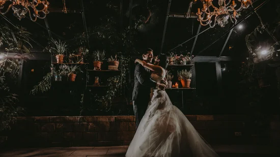 Brautpaar tanzt romantisch bei Nacht unter Kronleuchtern und Pflanzen